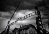 Nazi Slur Ignites Georgia Showdown Entrance gate with wrought-iron sign at a historic brick complex under stormy skies