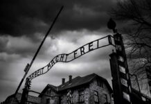 Nazi Slur Ignites Georgia Showdown Entrance gate with wrought-iron sign at a historic brick complex under stormy skies