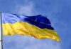 Moscow Hammers Kyiv’s Key Bridge Ukrainian flag waving on a flagpole against blue sky