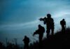Hostage Gambit: Bukele Threatens Massive Payback Silhouetted soldiers patrolling a hillside at dusk