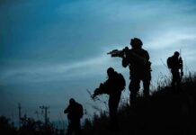 Silhouetted soldiers patrolling a hillside at dusk