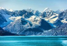 Glaciers Crash 20% – Alps Meltdown Accelerates Snow-capped mountains with glaciers above a turquoise lake