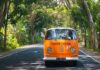 Orange vintage van driving on a tree-lined road