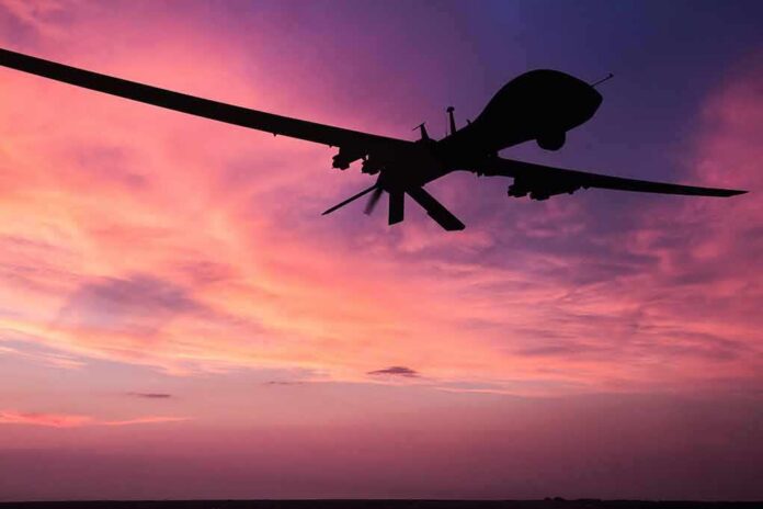 shutterstock_690489076 drone silhouette flying against a pink and purple sunset sky