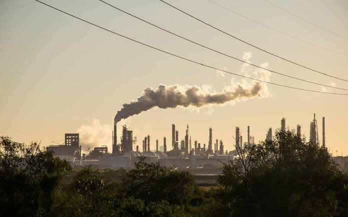 shutterstock_766204174 Industrial refinery with smokestack emitting plume at sunset